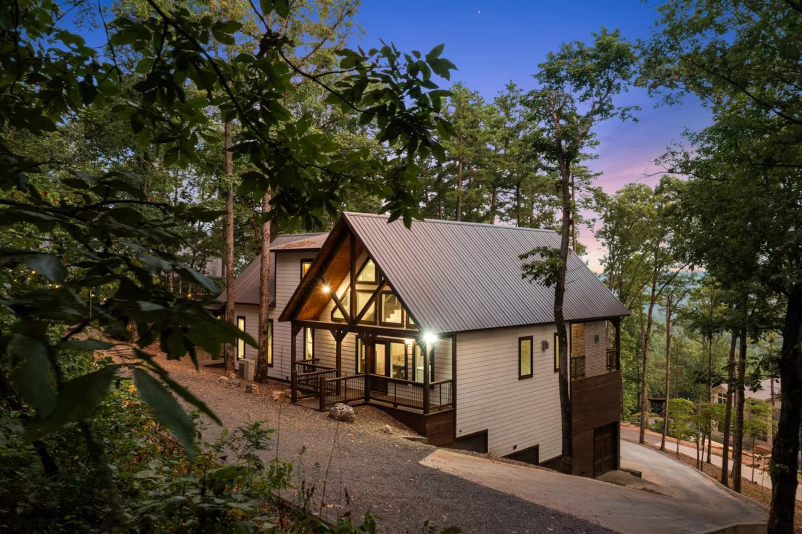 The cabin at twilight, seen from the drive under the pines.