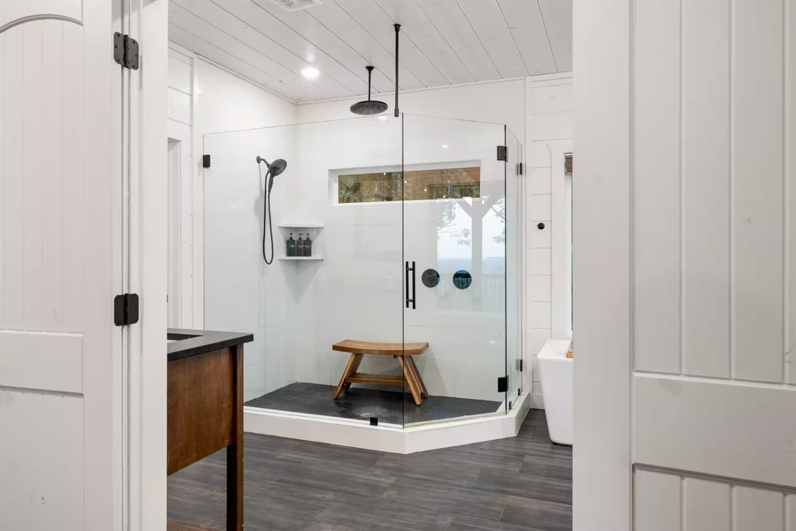 Walk-in shower with a glass enclosure and a teak bench.